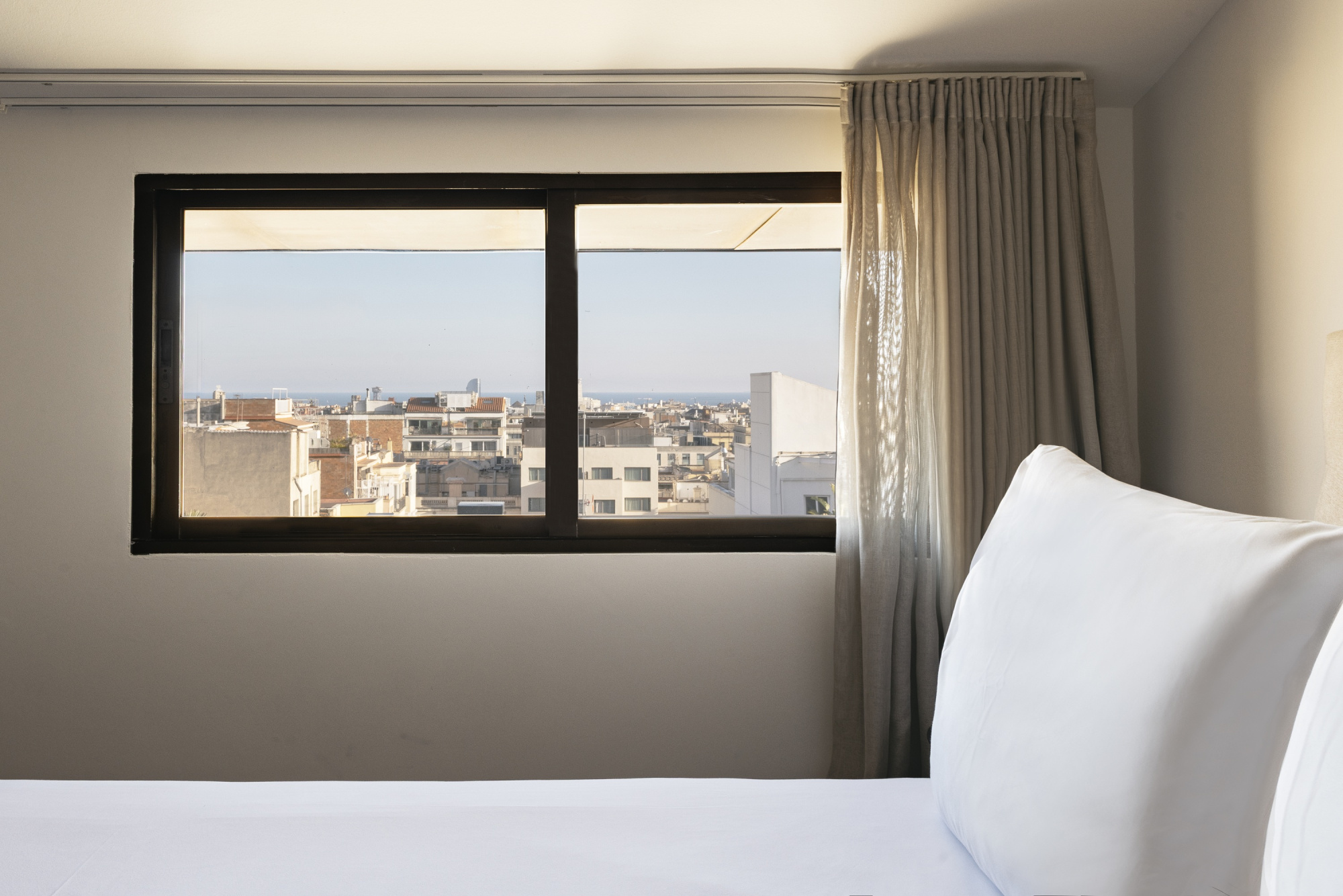 Una habitación de hotel moderna con decoración elegante, mobiliario en tonos neutros y una iluminación suave que crea un ambiente acogedor.