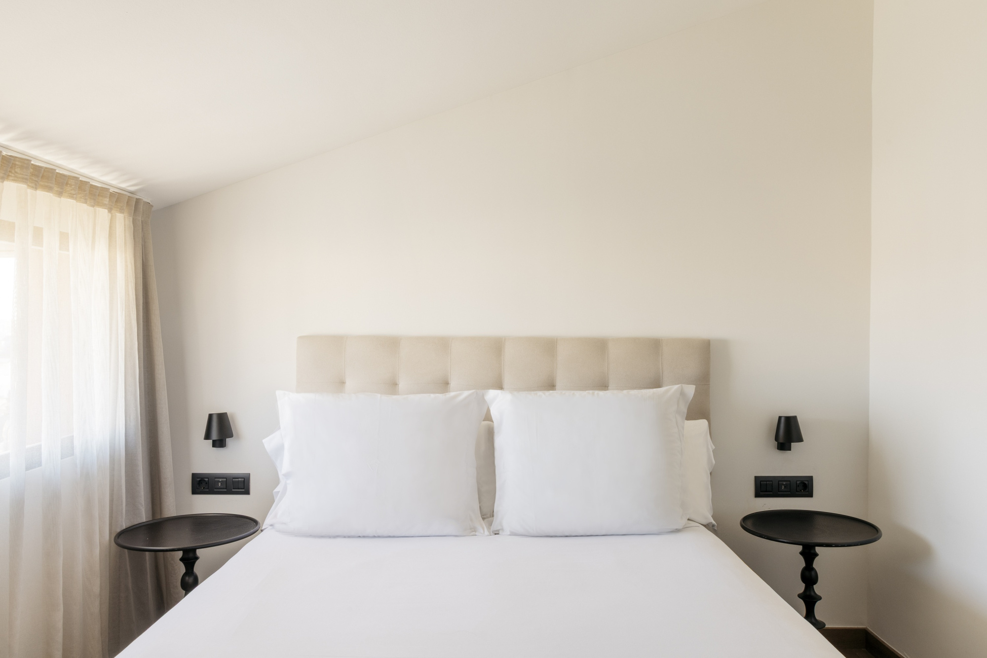 Imagen que muestra una habitación de hotel moderna y elegante, con decoración en tonos neutros y mobiliario contemporáneo.