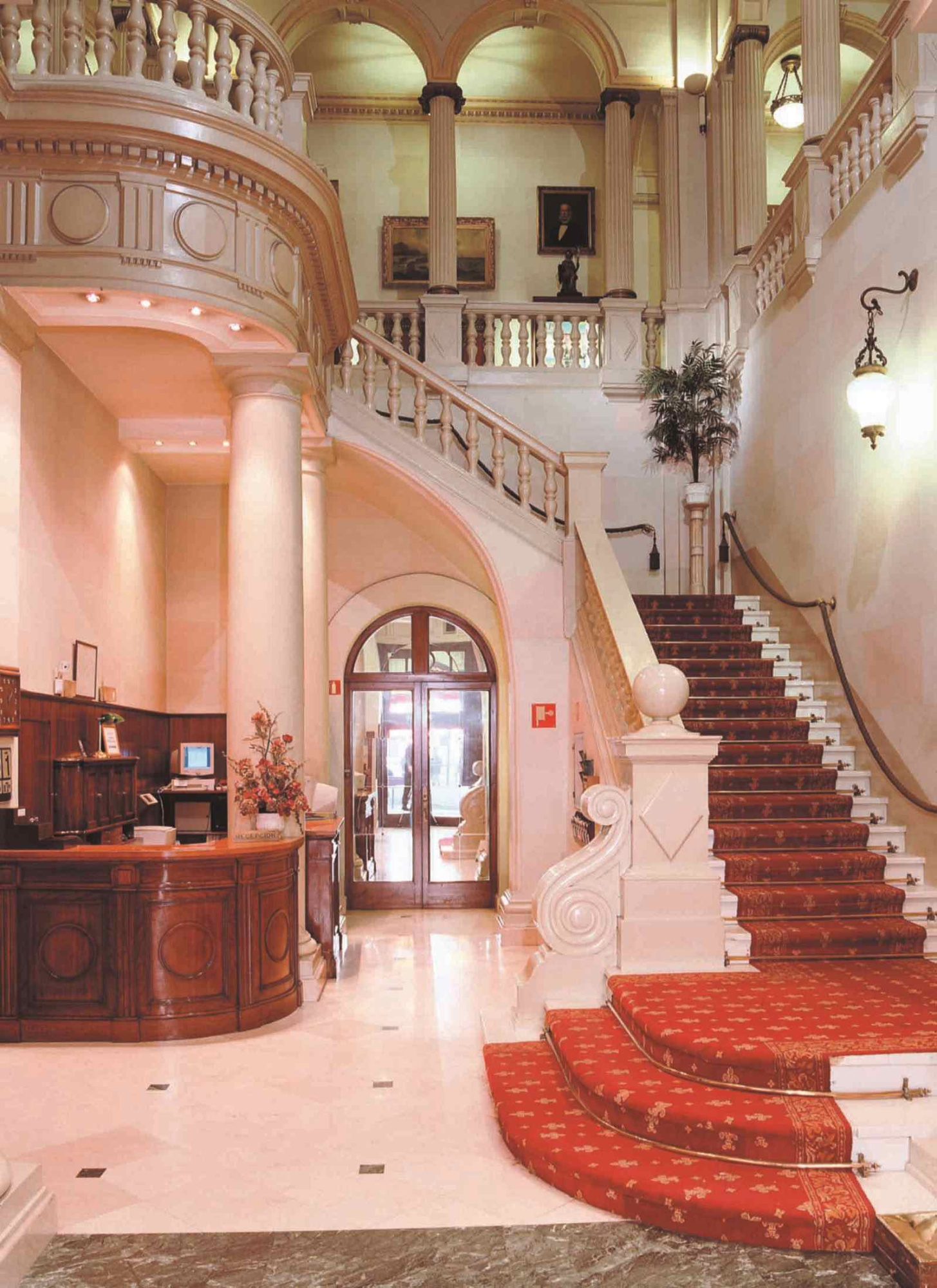 Zu sehen ist eine klassisch gestaltete Treppe mit Geländern und eine Lobby mit Marmorboden.
