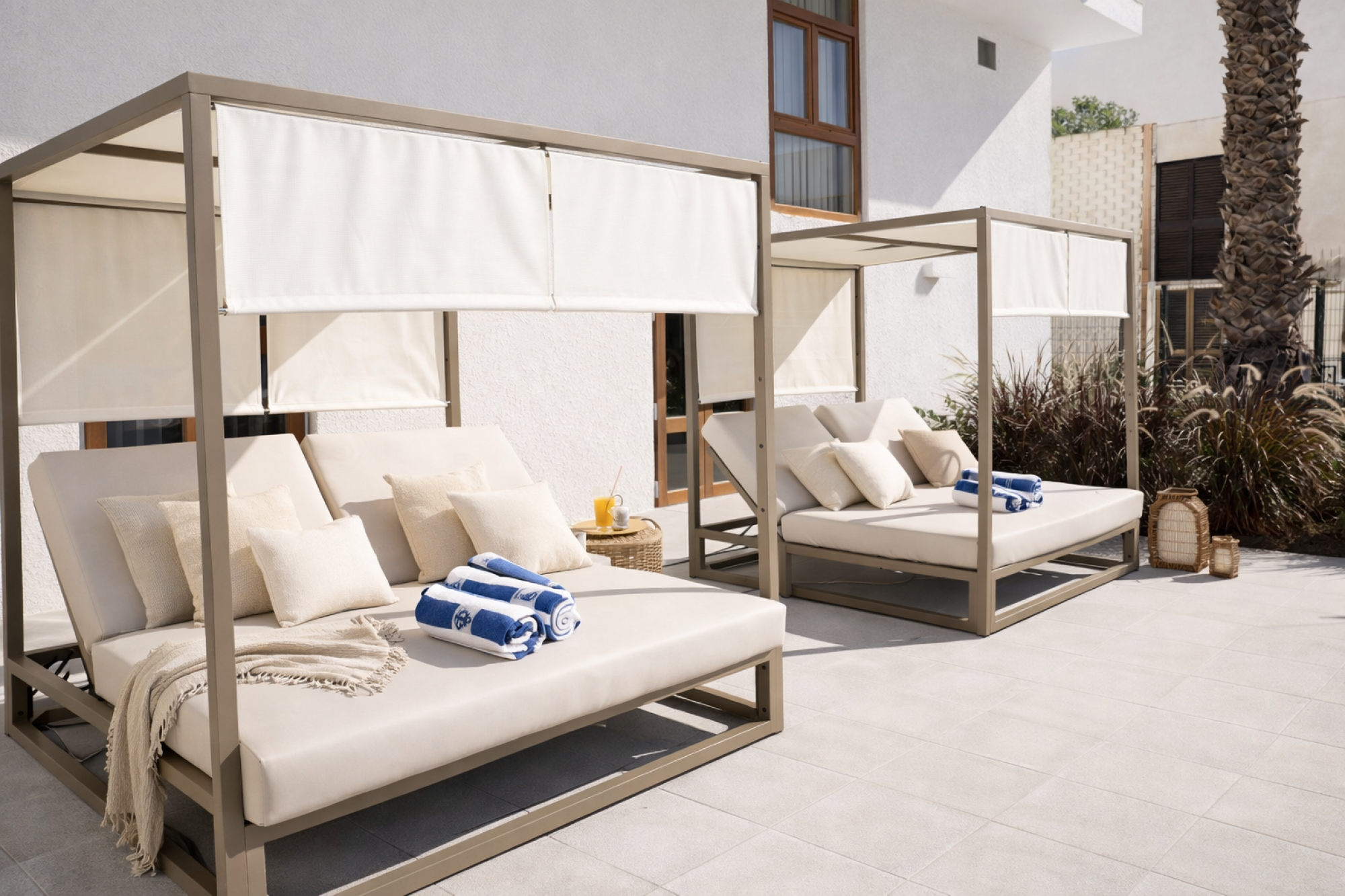 Una cama balinesa de madera oscura con un diseño tradicional, decorada con cortinas blancas que aportan un toque de elegancia y tranquilidad, ideal para ambientes de relajación en hoteles.