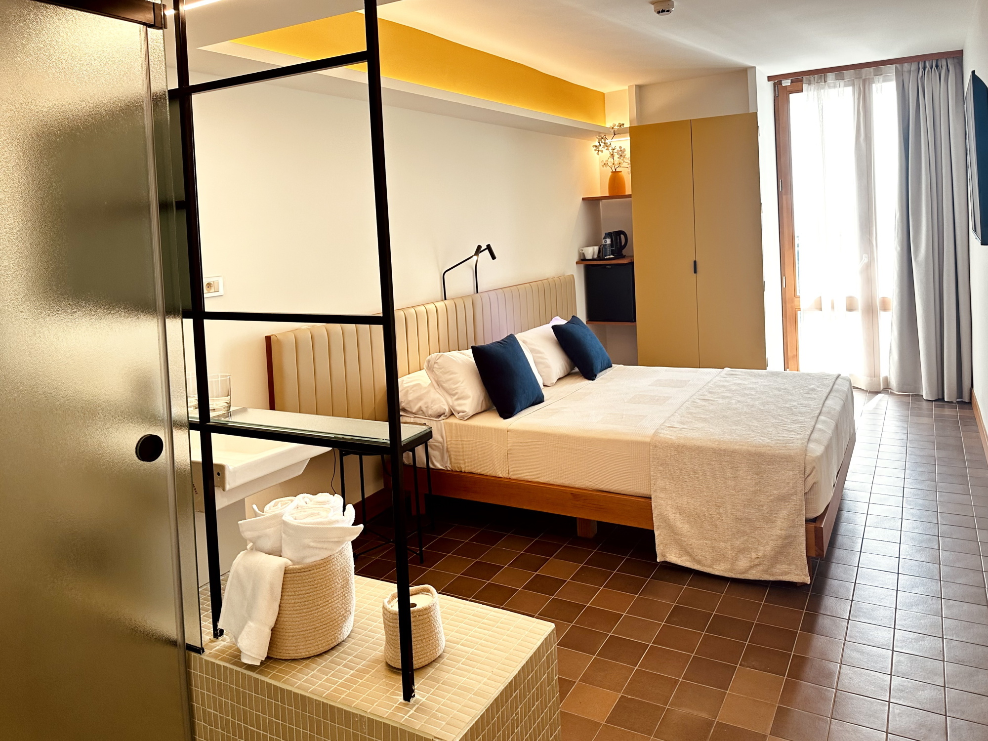 Imagen que muestra un entorno natural con vegetación y una estructura de madera, probablemente una terraza o área de descanso en un entorno costero o rural, con un estilo rústico y acogedor.