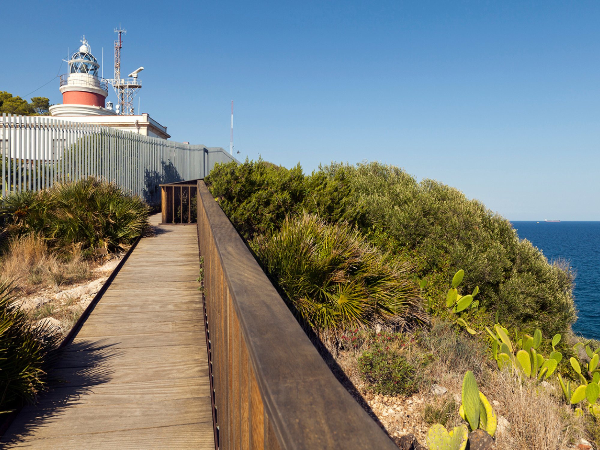 Vista panorámica de una playa con aguas cristalinas y arena dorada, rodeada de vegetación y colinas, ideal para actividades recreativas y relajación.
