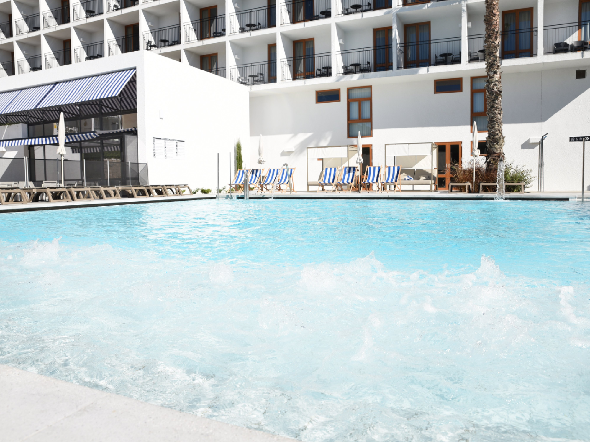 Una piscina al aire libre en el Hotel Sun Club Cala Vinya, rodeada de un entorno natural y áreas de descanso, perfecta para relajarse y disfrutar del sol.