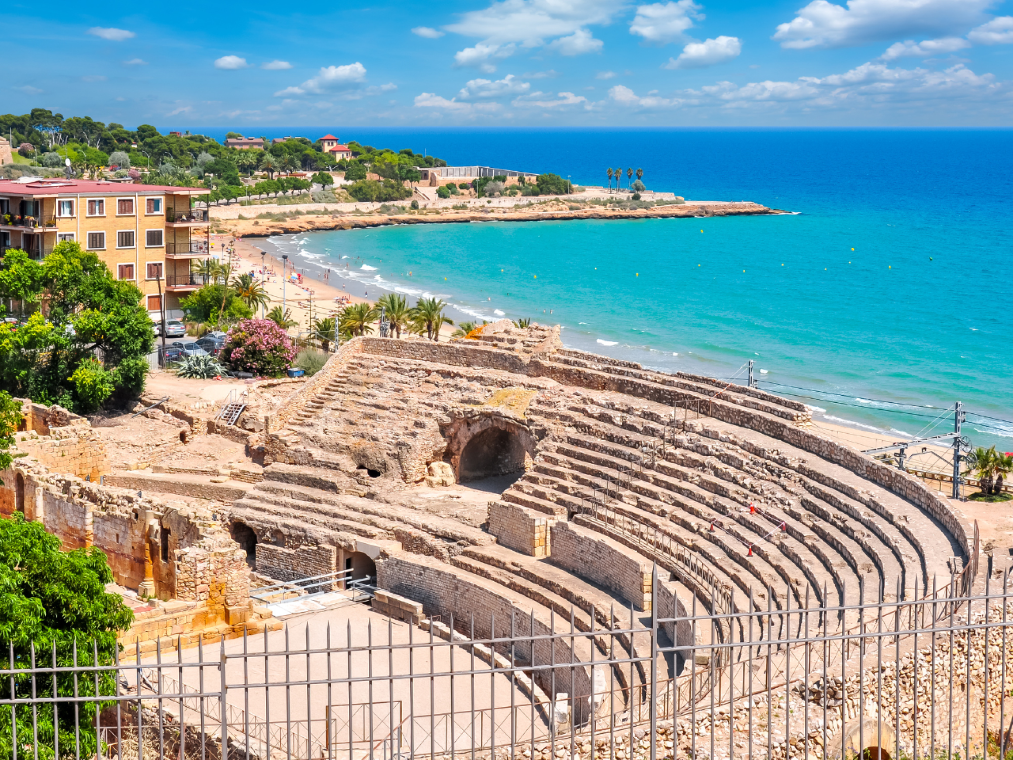 Vista exterior del Sun Club Hotel Cala Vinya, mostrando su arquitectura moderna y áreas de descanso al aire libre con vegetación y piscina, en un entorno costero.