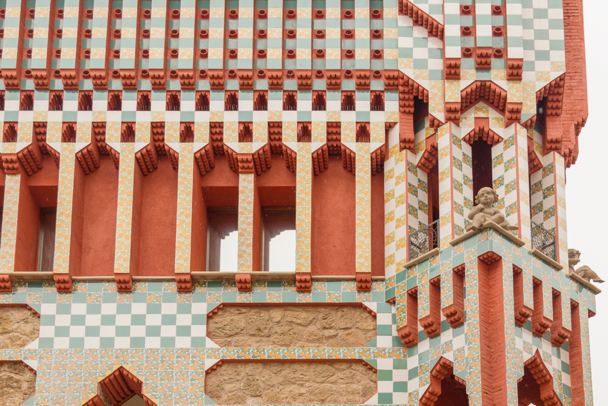 Una vista de la fachada de la Casa Vicens, diseñada por Antoni Gaudí, con detalles arquitectónicos distintivos y un estilo modernista. La estructura presenta colores vibrantes y detalles ornamentales.