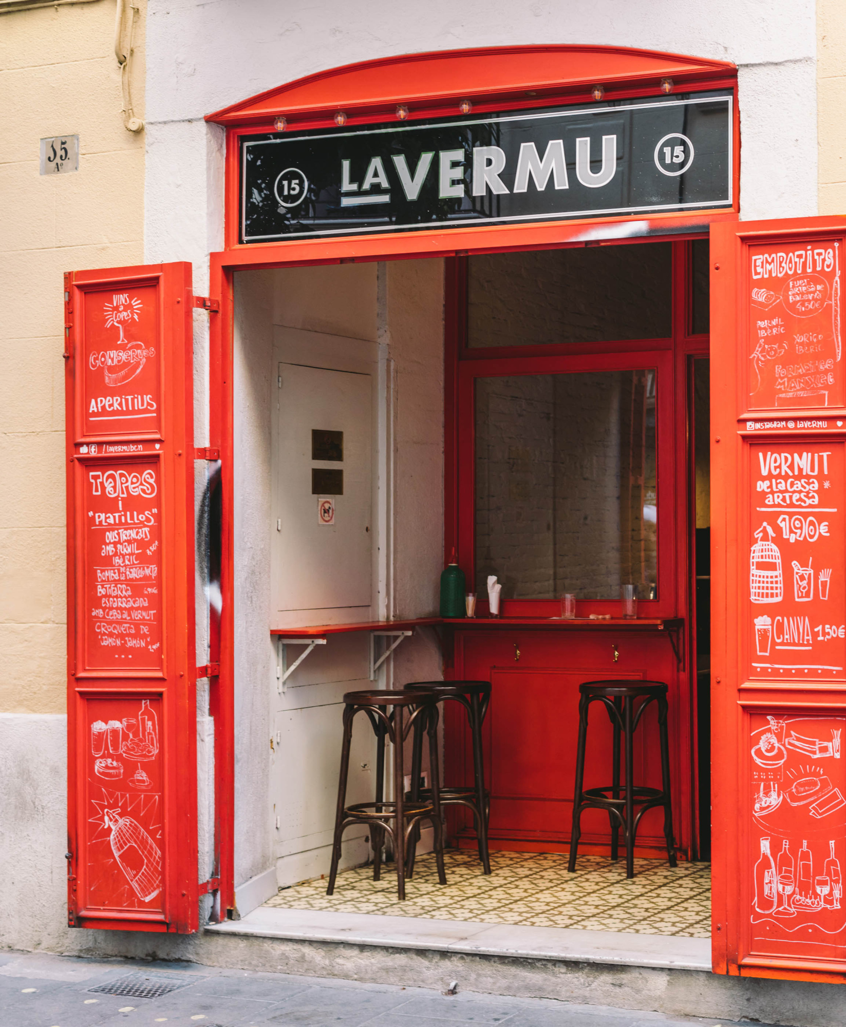 Un bar acogedor con una decoración moderna y cálida, que presenta una barra de madera y estanterías con botellas de bebidas, creando un ambiente invitador para los clientes.