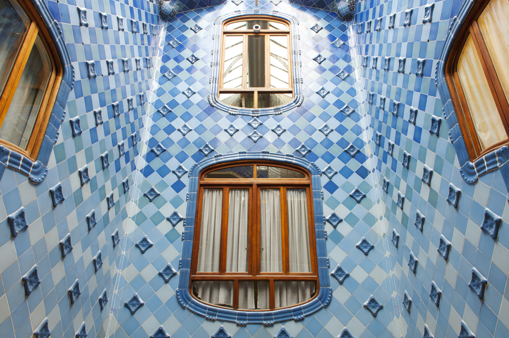 Se ve una pared interior con azulejos azules y ventanas con marcos de madera.