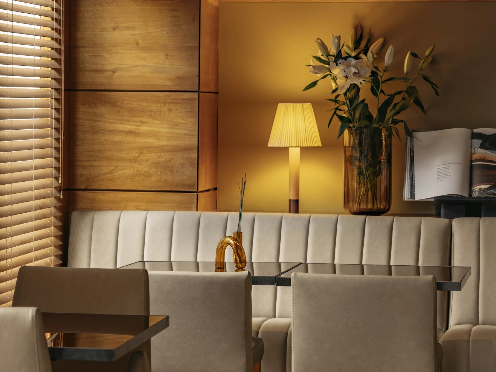 Se ve un área de estar con sofá, lámpara de pie y mesa auxiliar junto a una pared decorativa.