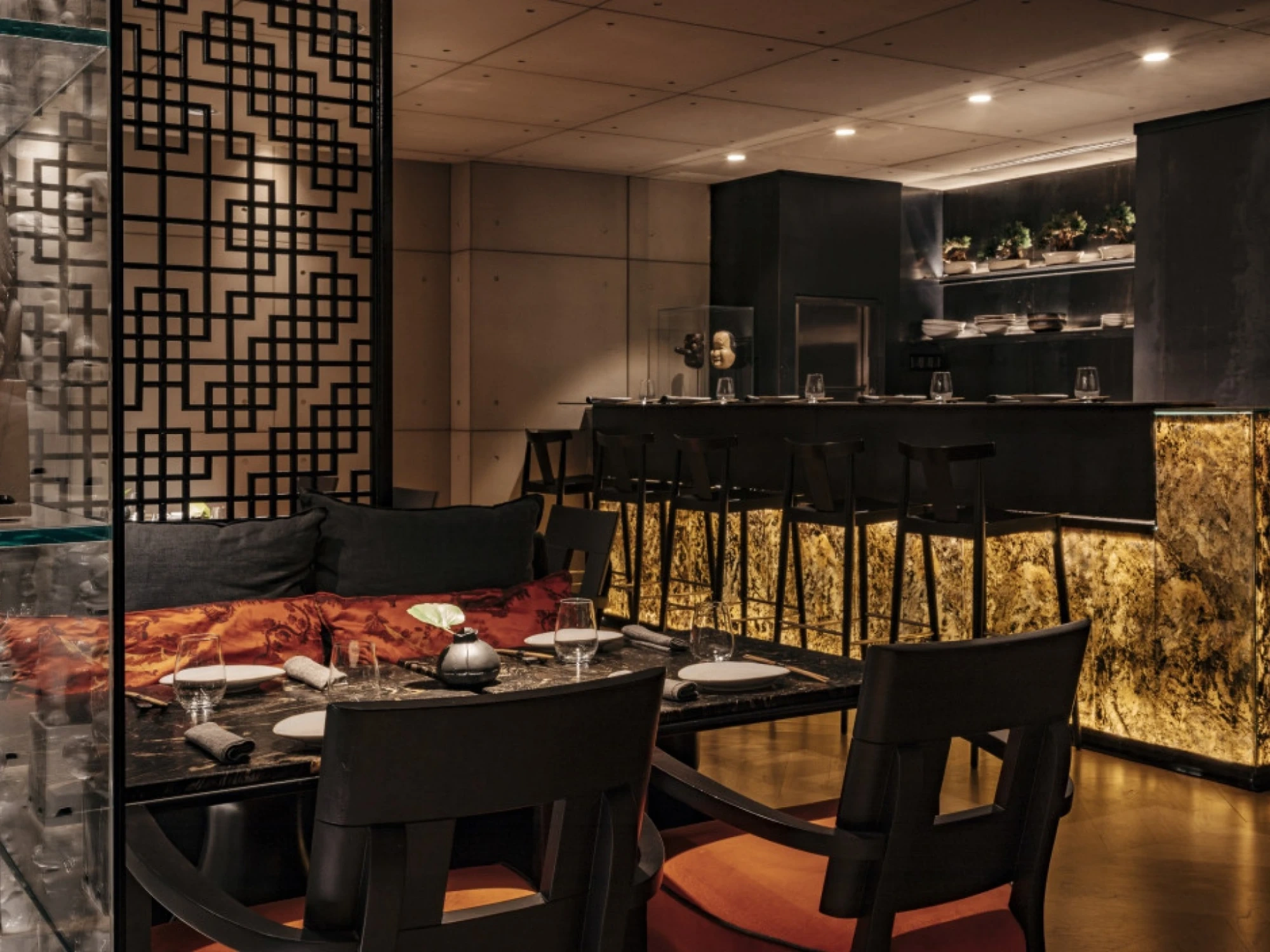Imagen que muestra el interior de un restaurante de sushi y robata, con un ambiente moderno y elegante, decorado con tonos oscuros y detalles en madera. La iluminación suave resalta la atmósfera acogedora.