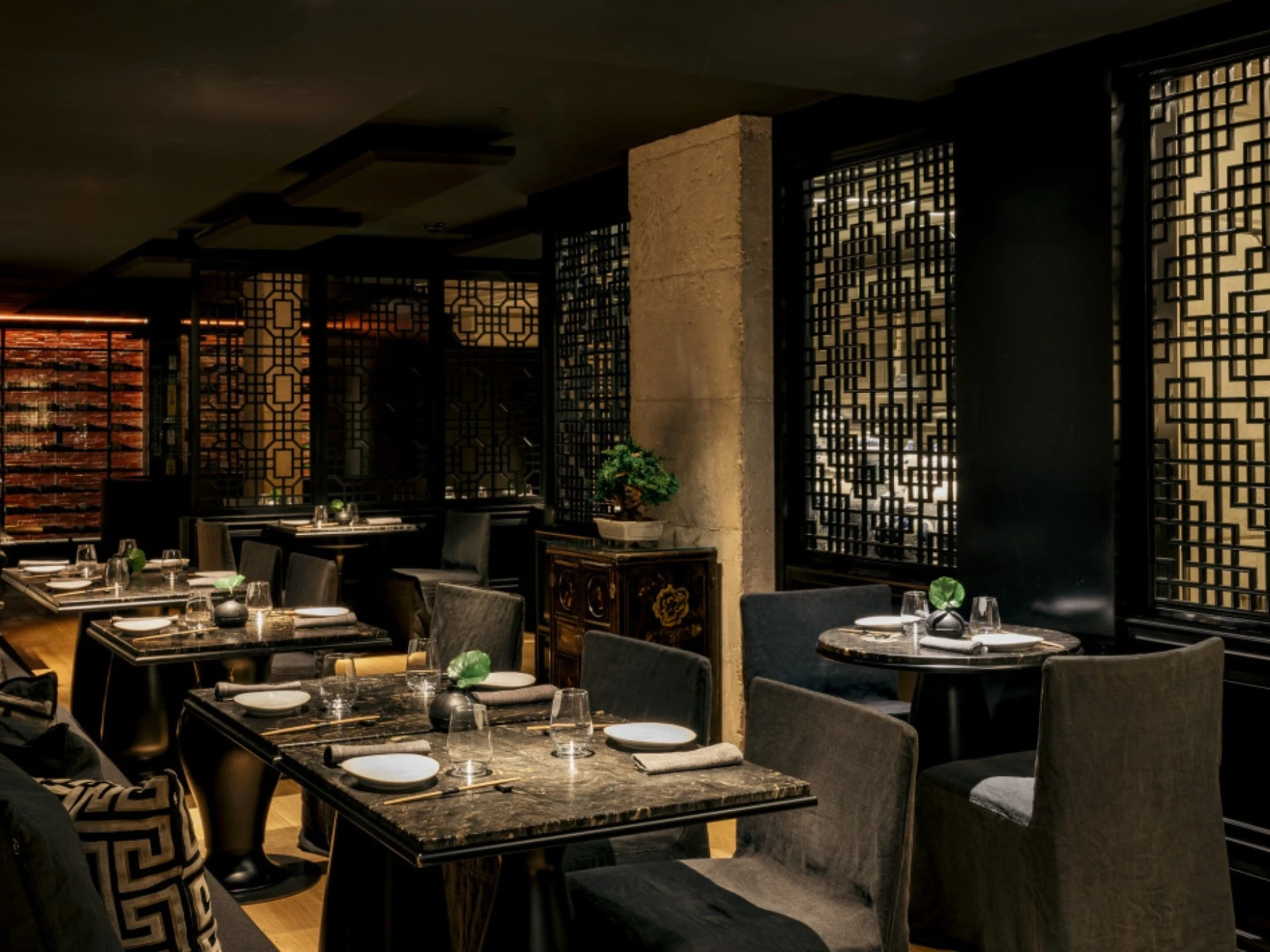 Imagen del interior del restaurante Os-Kuro Sushi Bar Robata, mostrando un ambiente moderno y elegante con decoración minimalista. La iluminación cálida resalta la barra y las áreas de comedor.